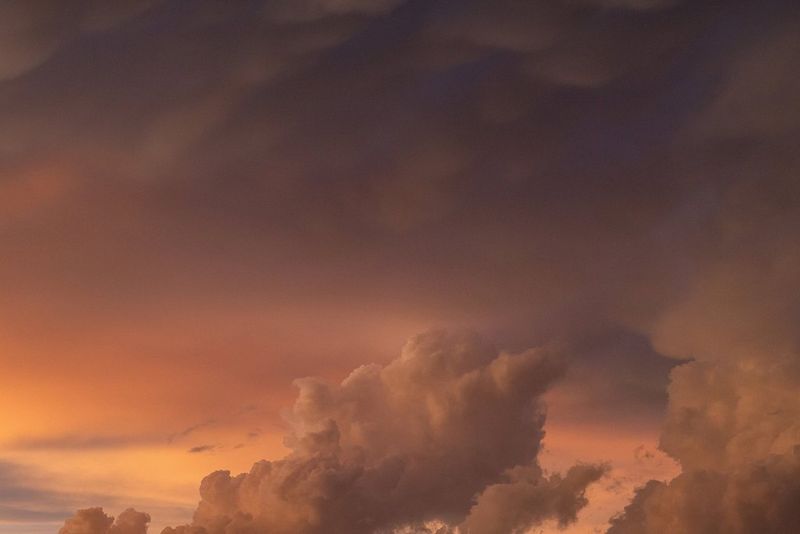Fluffy clouds captured against an orangery-purple sky. Taken on a Canon EOS 5D Mark III by Nico Schaerer.