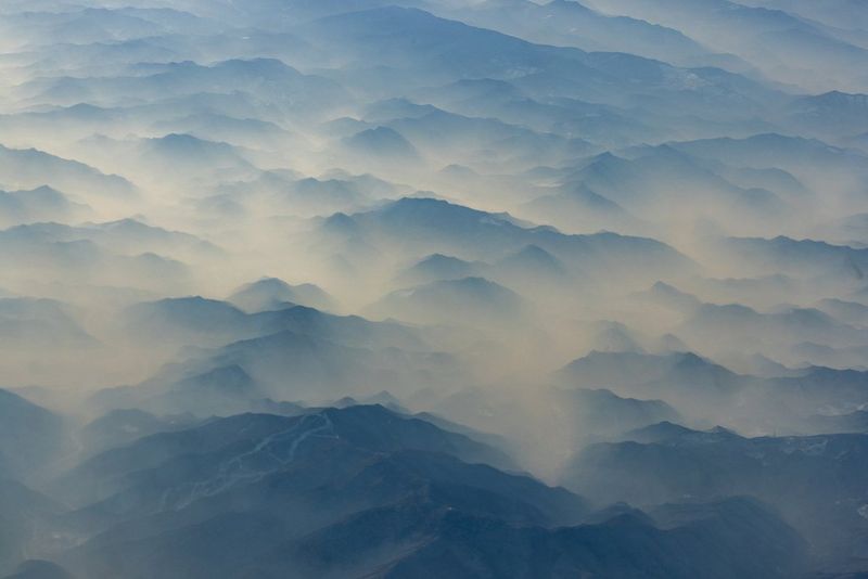 A mountain range in early morning light and bathed in a blue-tinged mist. Taken on a Canon EOS R5 by Nico Schaerer.