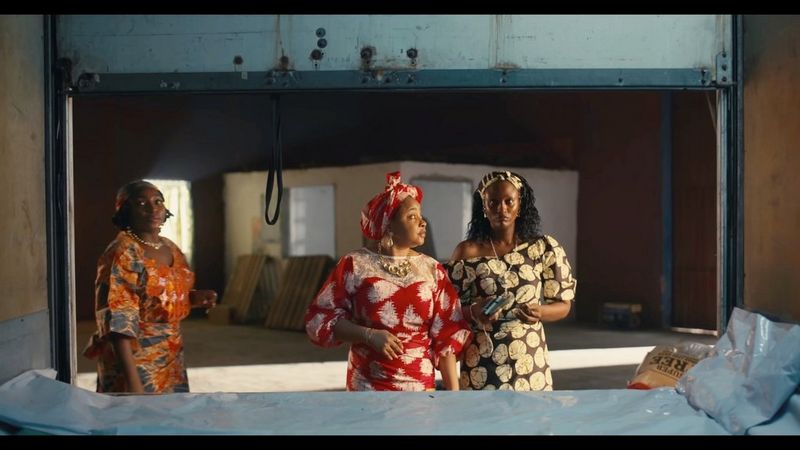 Three women standing behind an empty truck. Still from Black Market by Nora Awolowo.