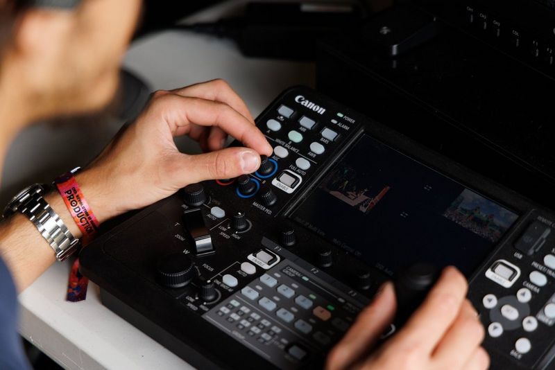 Hands operating a Canon RC-IP1000 PTZ controller.