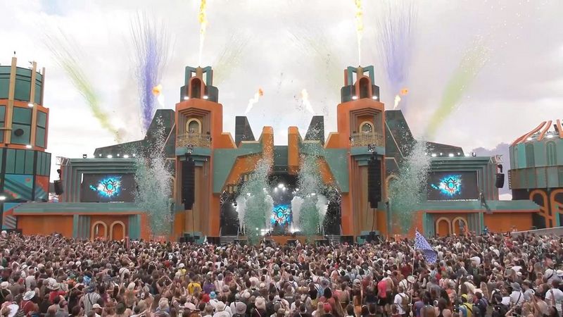 Crowds at a festival gathered around a large stage, fireworks exploding into the sky above. Still from a Boomtown video showreel by Southpoint Films.