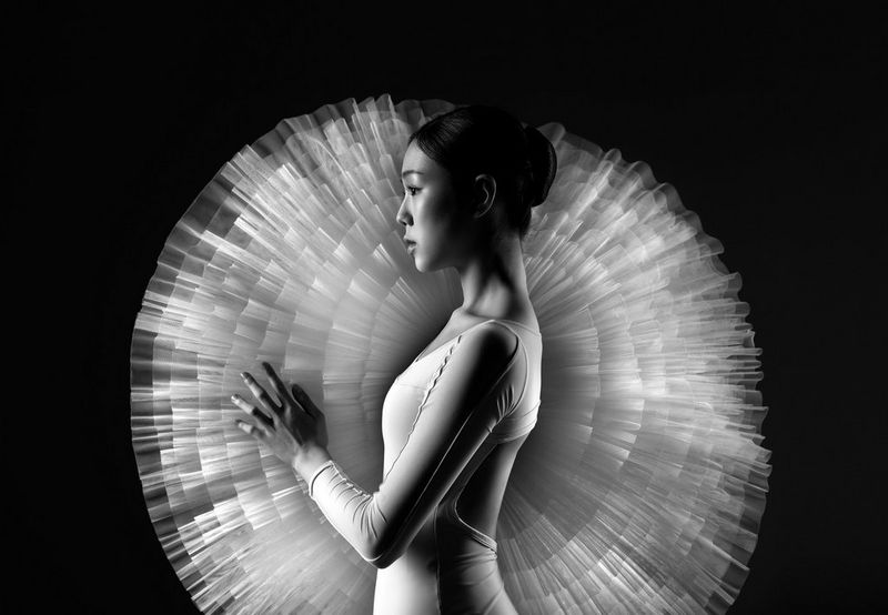 A black and white portrait of a ballet dancer framed by the net skirts of a tutu.