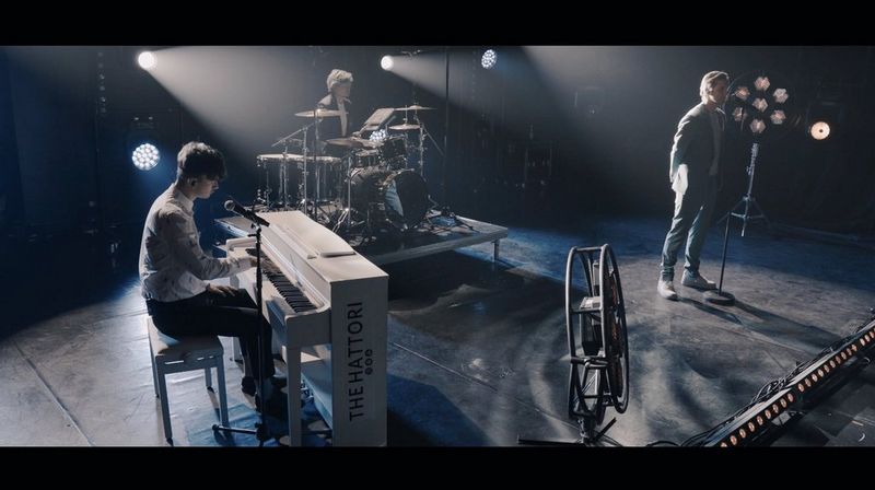 Three musicians performing on stage for a music video.