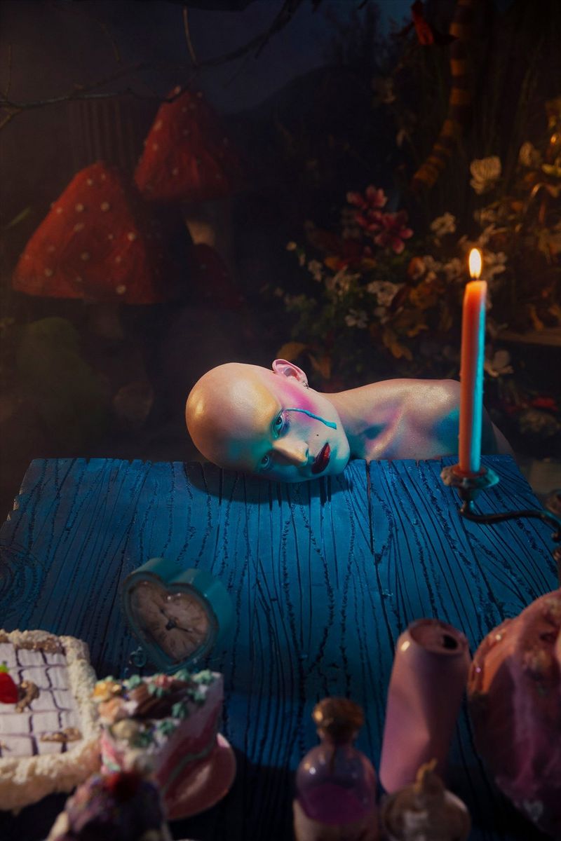 A portrait of a shaven-headed model resting their cheek on a blue wood-effect surface, with a light blue tear running down the side of their face. Taken on a Canon EOS 5DS by Canon Ambassador Sébastien Salamand dit Le Turk.