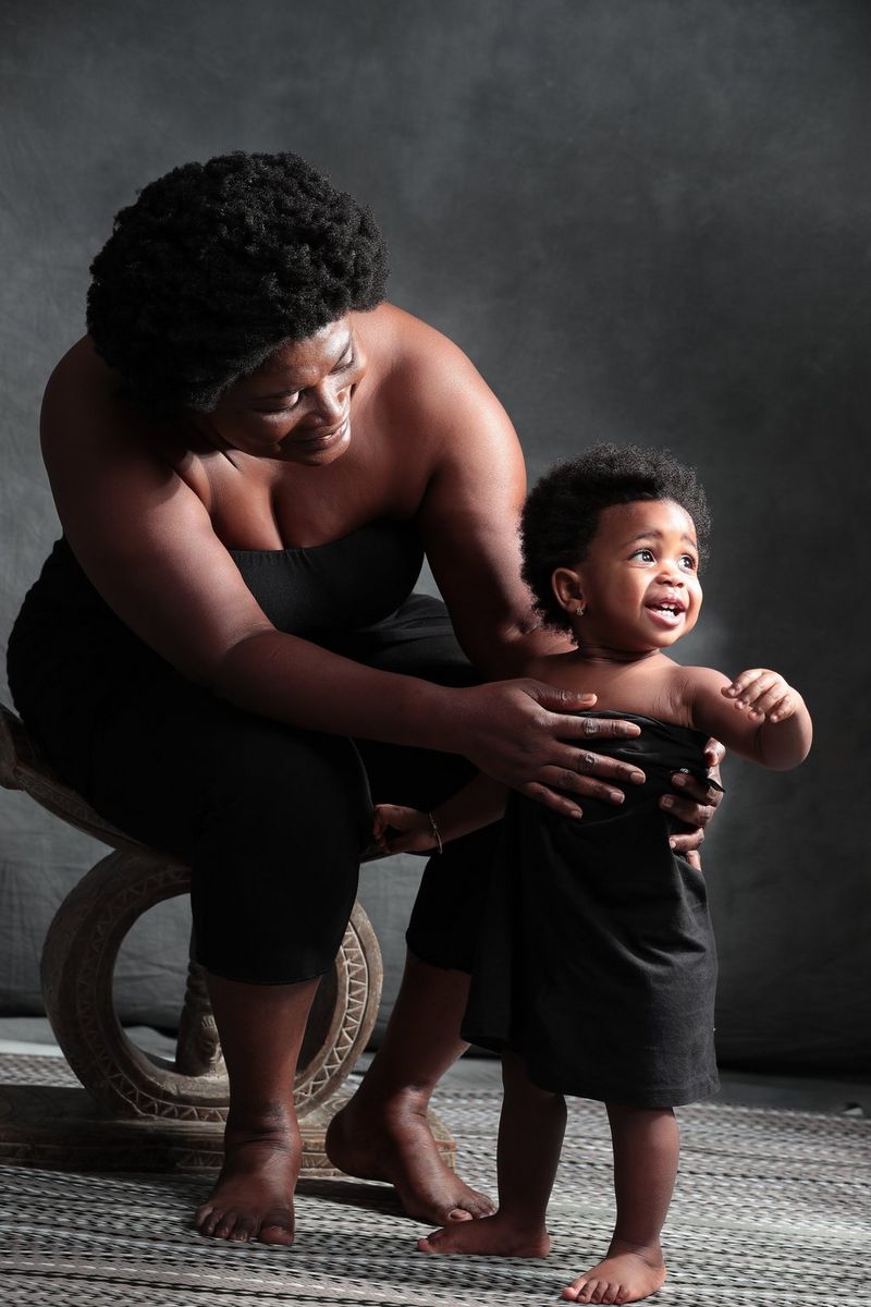 A portrait of a woman sitting on a chair and holding her smiling child. Taken on a Canon EOS-1D X Mark II by Canon Ambassador Seibou Traoré.