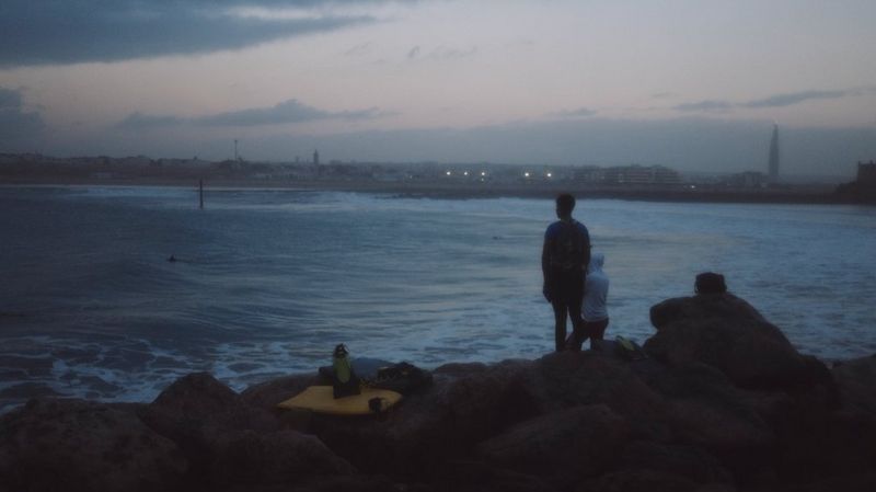 A still from filmmaker and Canon Ambassador Szymon Dudka's Morocco showreel, showing two figures standing on rocks next to the ocean. Shot on a Canon EOS R6 Mark II.