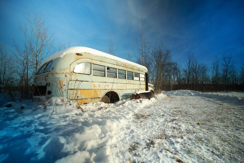 A pale green abandoned school bus sits in piled-up snow, in a still by Canon Ambassador Tanya Aizikovich.