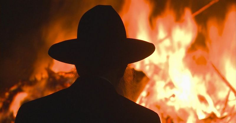 A man in a wide-brimmed hat is silhouetted against a bonfire, in a still from Messiah, captured by cinematographer Tanya Aizikovich.