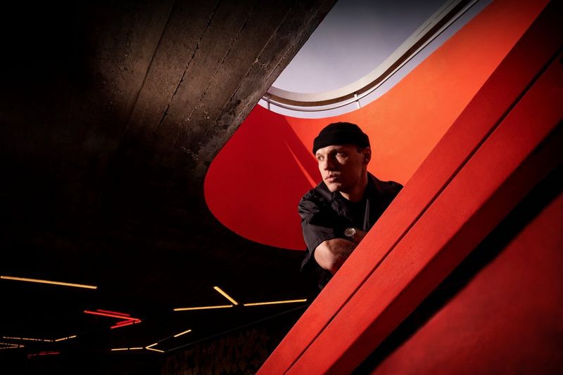 A portrait of Czech rapper Viktor Sheen, leaning over the edge of a red stairwell with the sky visible above him, taken on a Canon EOS R5 by Tomáš Třeštík.