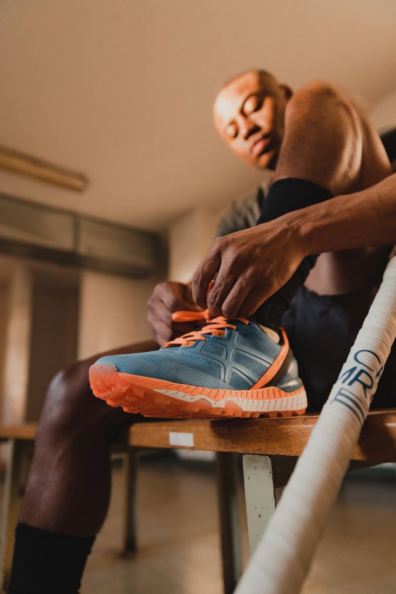 A man, slightly out of focus, sits on a chair and ties his left shoelace. The colourful shoe is in focus. Taken on a Canon EOS R5 by Canon Ambassador Tristan Schäfer.