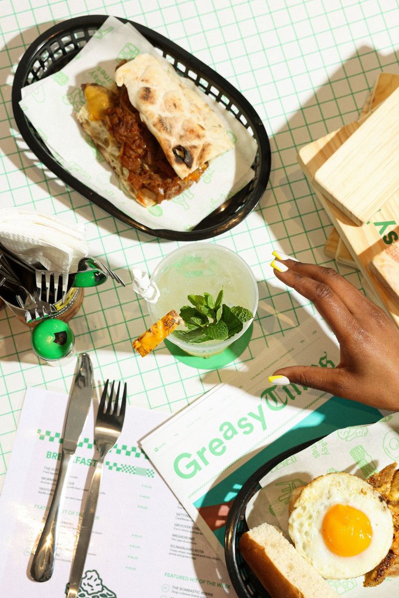 An overhead shot of a person's hand reaching out to a drink decorated with mint leaves. The drink is surrounded by cutlery and other food. Taken on a Canon EOS R5 by Canon Ambassador Tristan Schäfer.