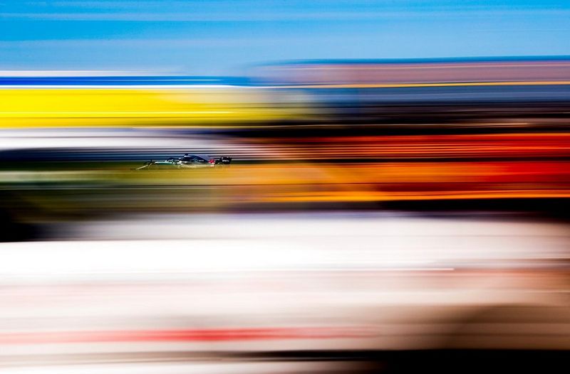 A shot of a racing car taken with a long exposure to create streaks of colour across the image. 