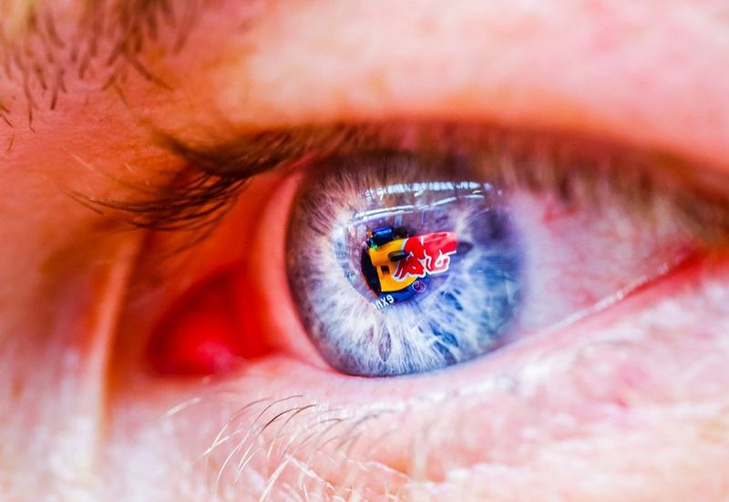 A close-up of an eye with a racing car reflected in the pupil.   