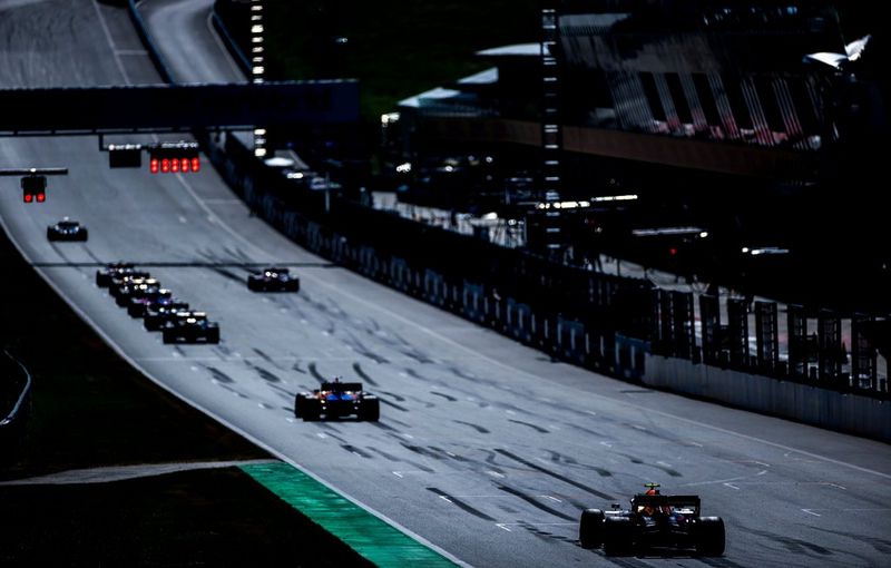 Racing cars arrive on the grid for the start of practice.