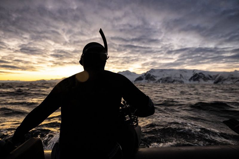 The silhouette of Stéphane Granzotto, wearing a wetsuit and snorkel, as he prepares to jump into the Arctic Ocean.
