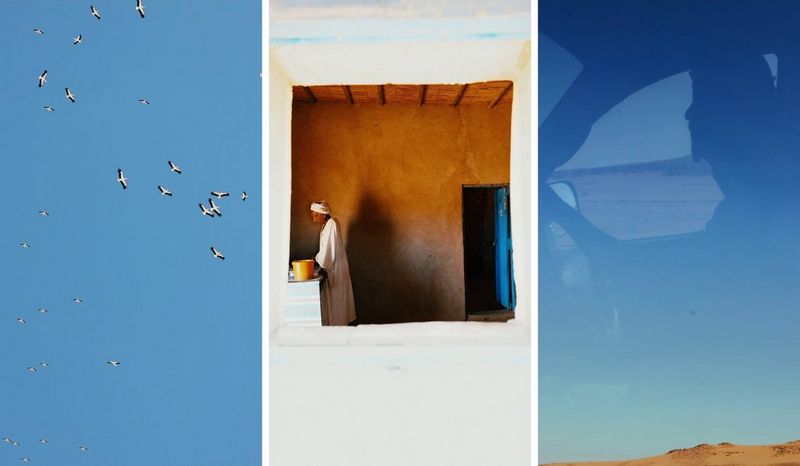 A triptych of birds flying around a bright blue sky; a man in long white robes standing by a worktop, photographed through a window in a white wall; and a reflection of a car driver in a car window, through which can be seen a bright blue sky and land. Shot by Camilla Ferrari.