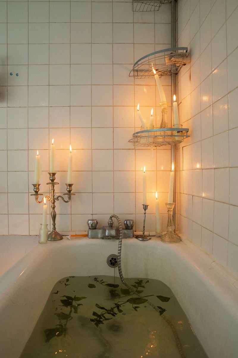 Foglie galleggiano in una vasca da bagno decorata con candelabri accesi in una foto scattata da Wanda Martin.