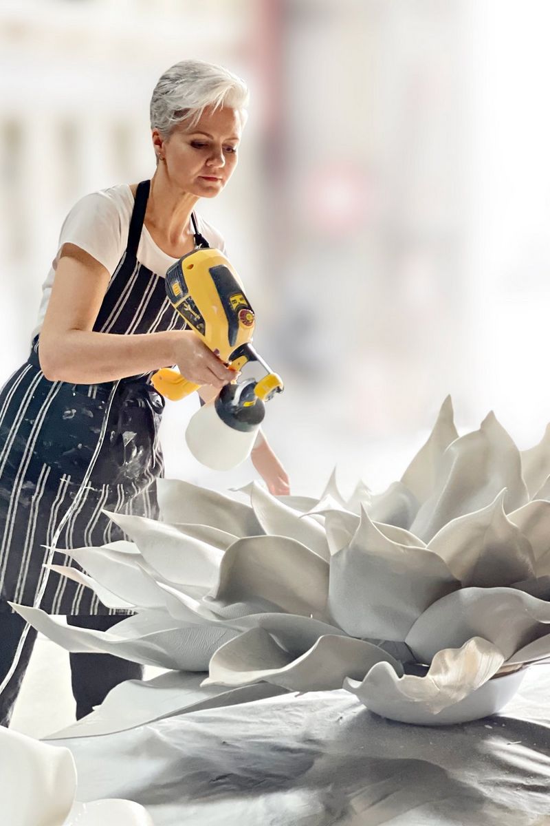Photographer Kelly Brown spray paints a large white flower in preparation for a series of newborn portraits.