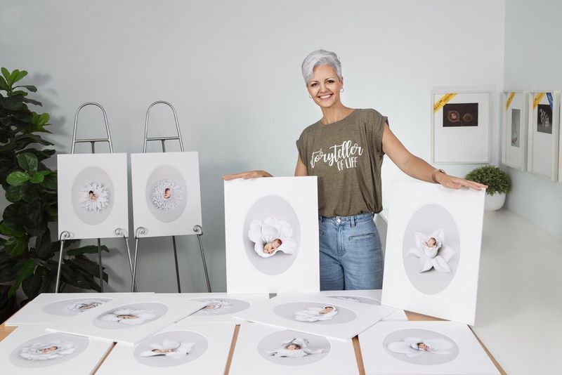 Photographer Kelly Brown stands displaying her series of newborn baby portraits that earned her a Fellowship Distinction from the Society of Wedding and Portrait Photographers.