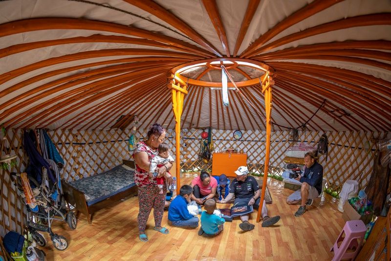 Clemens Boecker films Joey Kelly and Mongolian nomads seated in the centre of a tent with red and white striped roof.