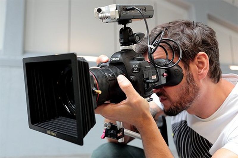 A man filming with the Canon EOS 5D Mark IV rigged for video. 