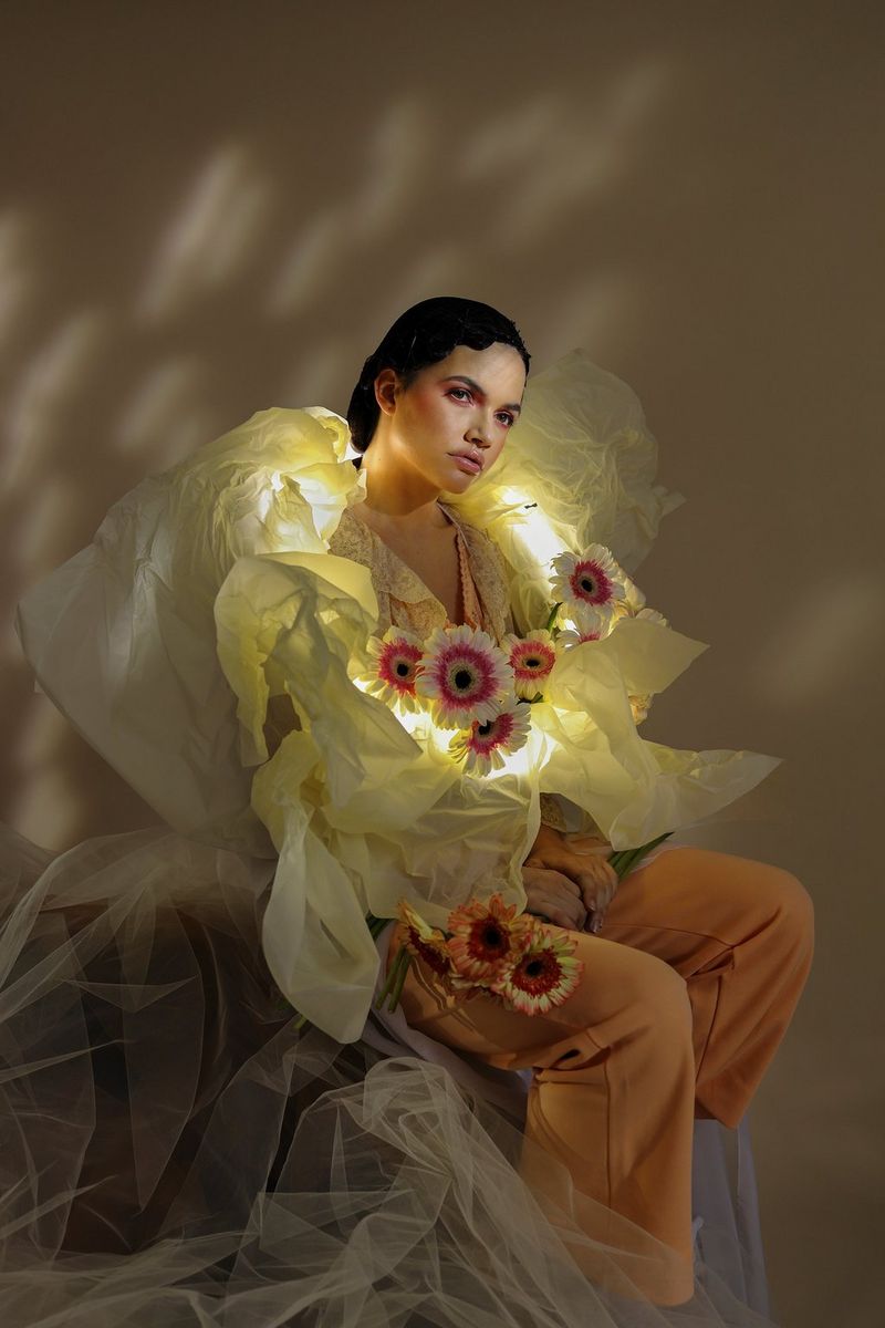 A portrait of a model wearing a yellow outfit covered with flowers. 
