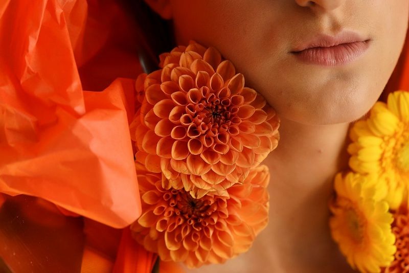 A close-up portrait of a model wearing flowers around her neck. 