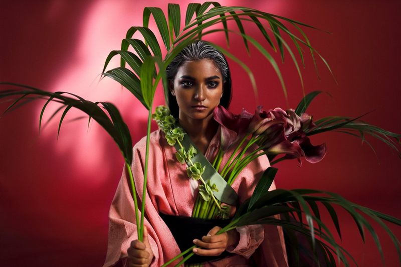 A model stands amid tropical flowers and plants. 