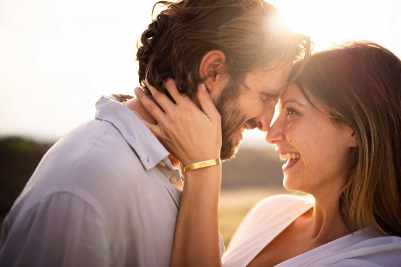 A close-up shot of a laughing couple, their faces bent together so their noses and foreheads are touching.