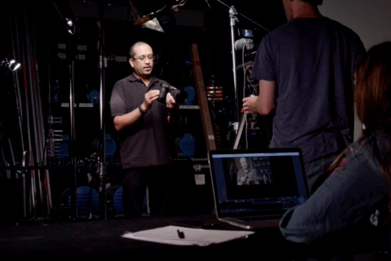 Een presentator die een camera vasthoudt, wordt gefilmd in een studio met een Canon EOS C70 terwijl iemand anders de stream bekijkt op een laptop.