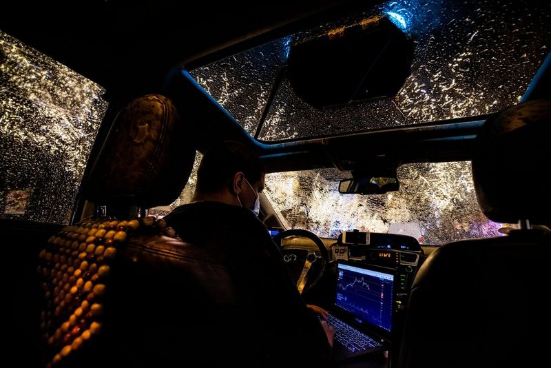 A masked French taxi driver types on his laptop while waiting for customers during the Covid-19 pandemic.