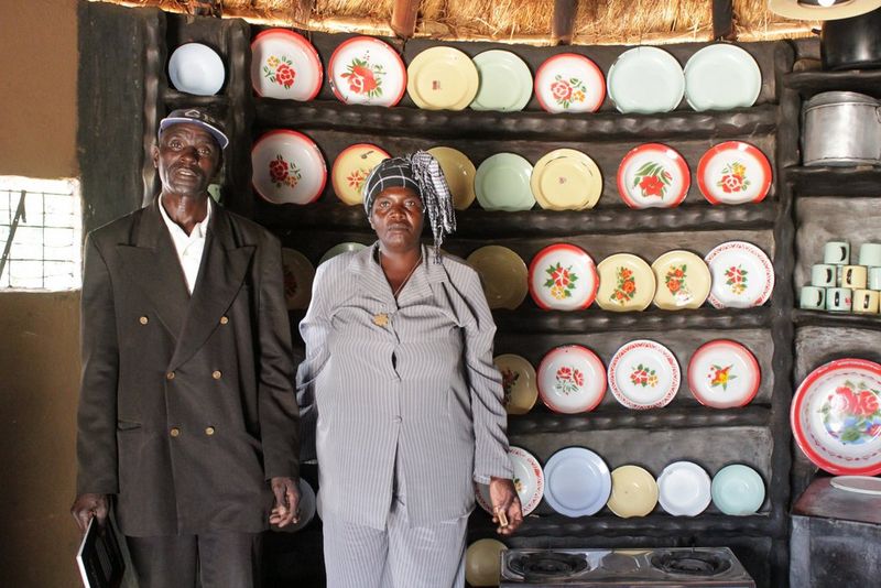 Marito e moglie davanti a un'esposizione di piatti colorati nella loro casa alimentata a biogas, in uno scatto di Angela Jimu.