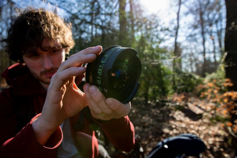 Cinematograaf Freek Zonderland houdt in een bosrijke omgeving een Canon Sumire Prime vast en kijkt door het objectief.