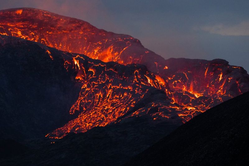 Lavapaden met een oranje gloed stromen over de zijkanten van een vulkaan.