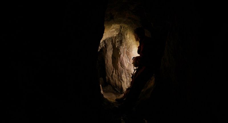 A film still of a silhouette of a male miner underground, captured on the Canon EOS C70 cinema camera. 