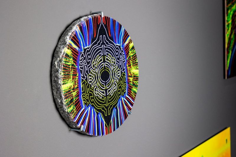 Een kunstwerk van studente Matilde Merli dat is geprint op een rond stuk steen en op een tentoonstellingswand is gehangen.