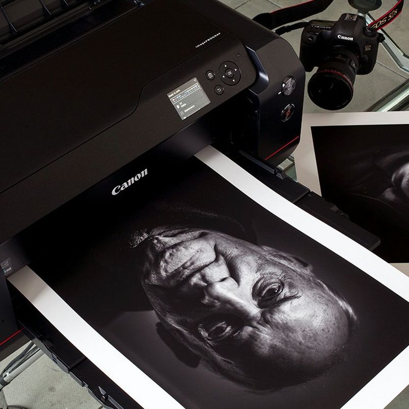 A Canon printer printing out a black and white portrait of an older man.