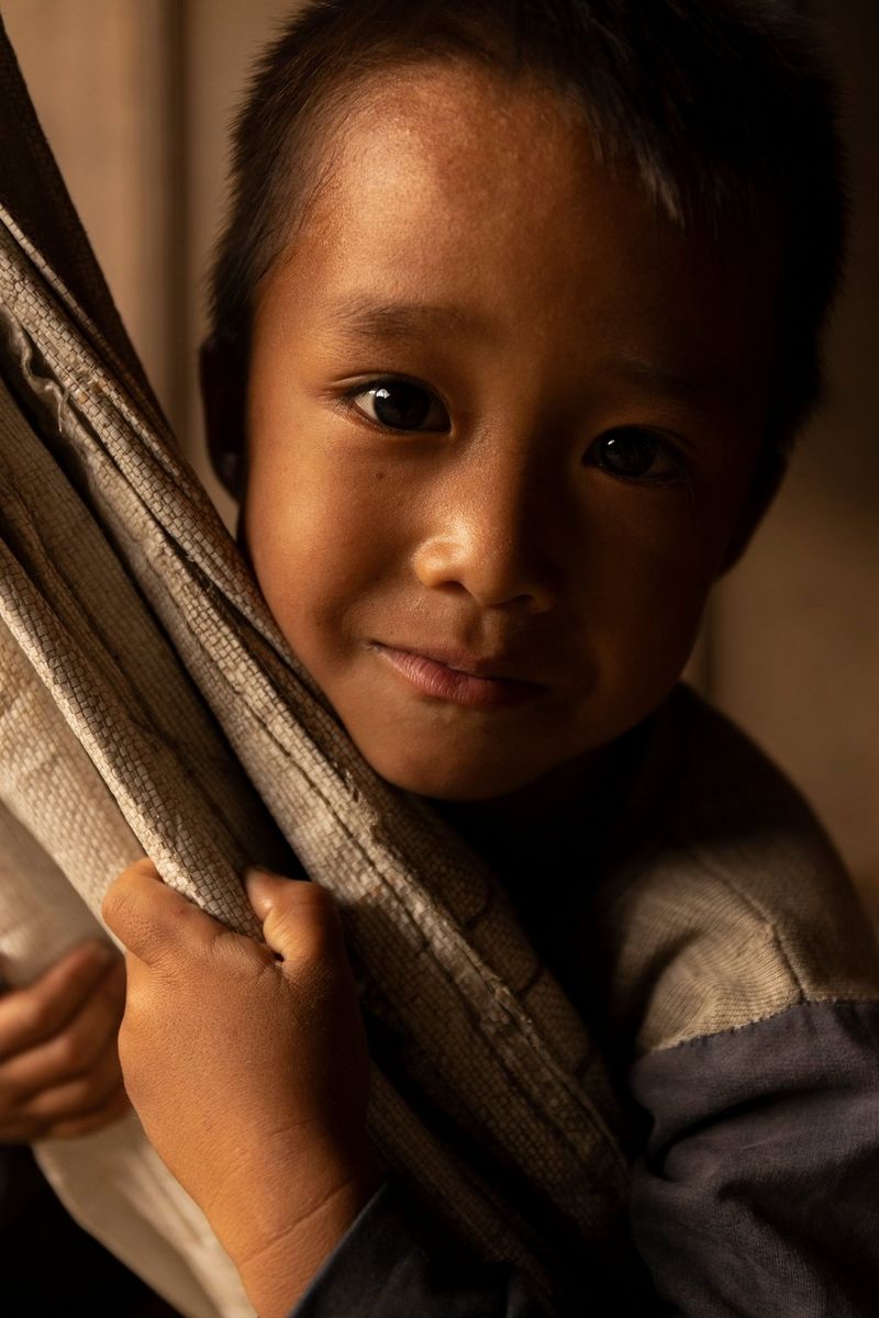 A close-up portrait of a young boy in Vietnam, taken on a Canon EOS R5 using autofocus to ensure his features are clear and sharp. 