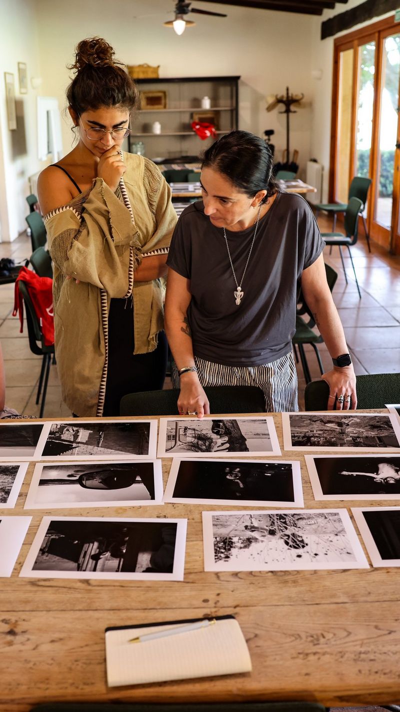 Two women looking at photographs on a table.