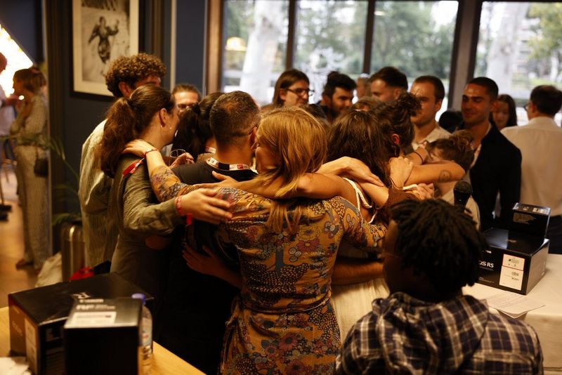A group of people in a circle in a function room, hugging.