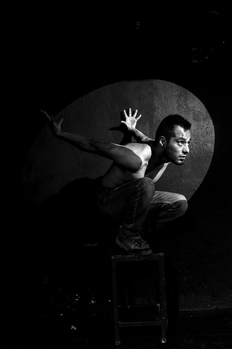 A man kneeling on a stool with his arms stretched out behind him. Photo by Eleni Albarosa