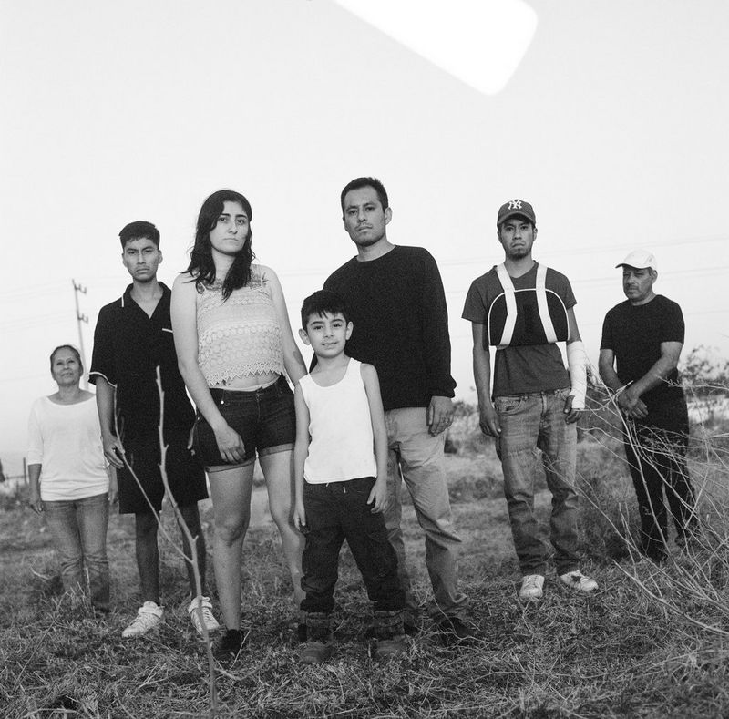 A family standing in a field looking down the lens of the camera. Photo by Eleni Albarosa