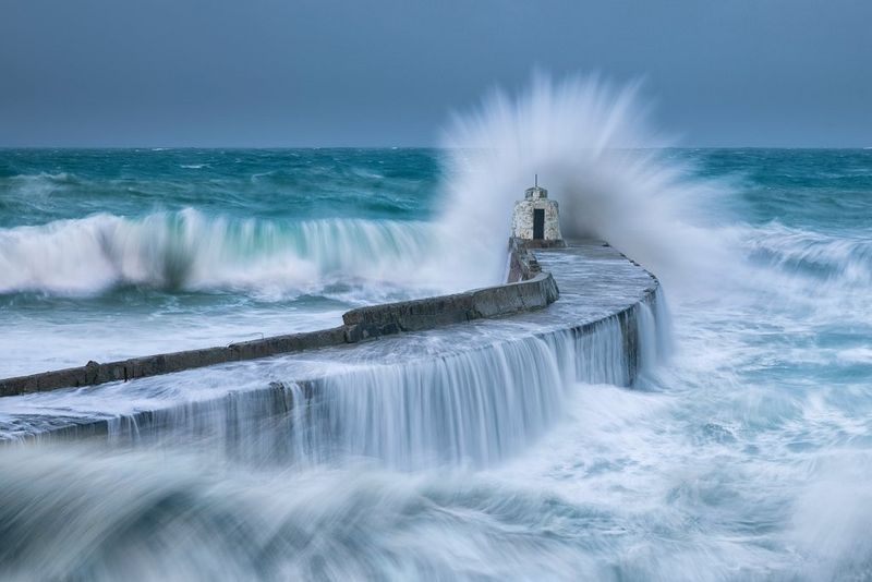Waves battering a harbour wall during a storm. A long exposure has blurred the movement of the water.