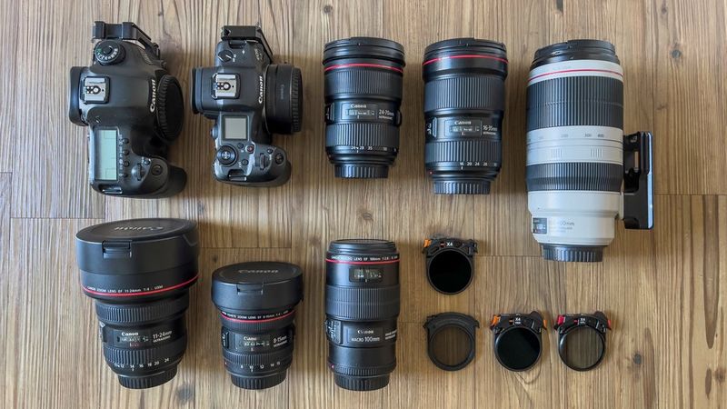 Canon cameras, lenses and drop-in filters arranged on a wood-effect surface.