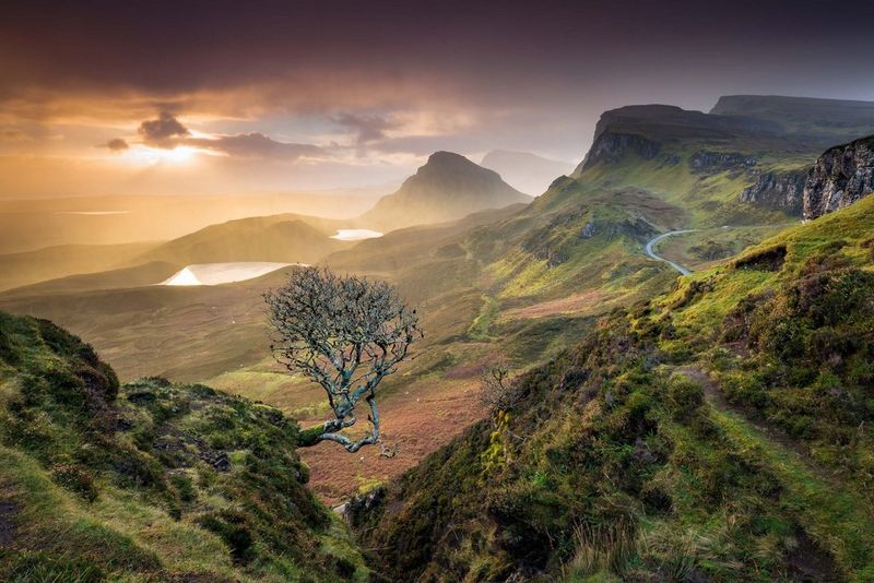 Un paysage spectaculaire de montagnes rocheuses couvertes de feuillage avec le soleil se levant au-dessus, adoucissant le ciel, pris dans le Quirraing, Skye. Photo prise avec un appareil Canon.