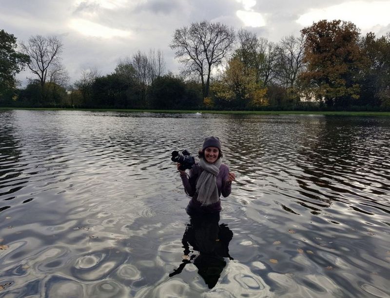 Элиза Яннаконе держит в руках камеру Canon, стоя по колено в воде.