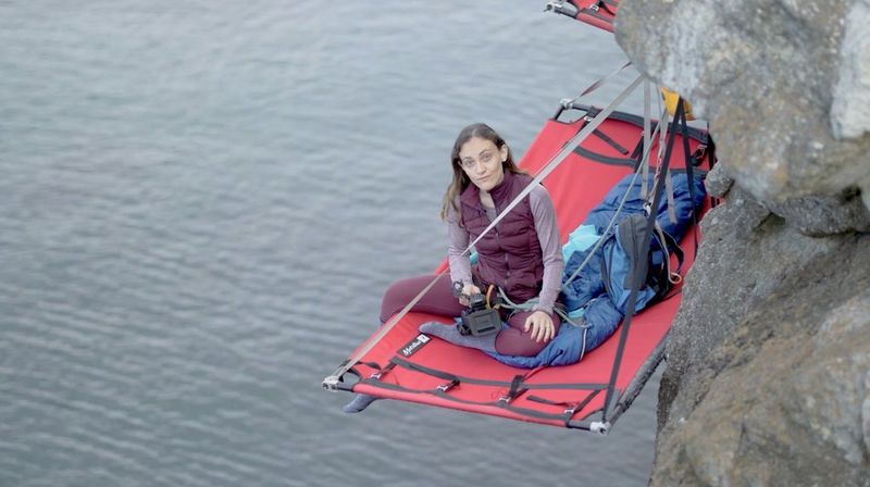 Журналист Элиза Яннаконе сидит на платформе для сна, подвешенной к скале на территории Уэльса.