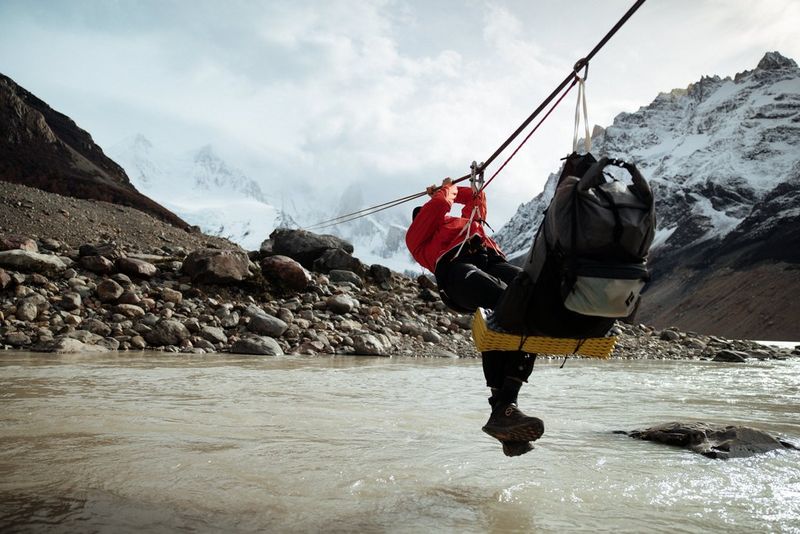 A man pulls himself along a line suspended over a river in Patagonia.