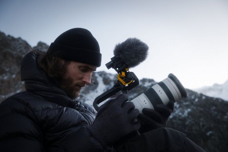 Daniel Ernst in a frozen Patagonian landscape, looking at the rear screen of his Canon EOS C50 which has a Canon RF 70-200mm F2.8L IS USM Z attached.