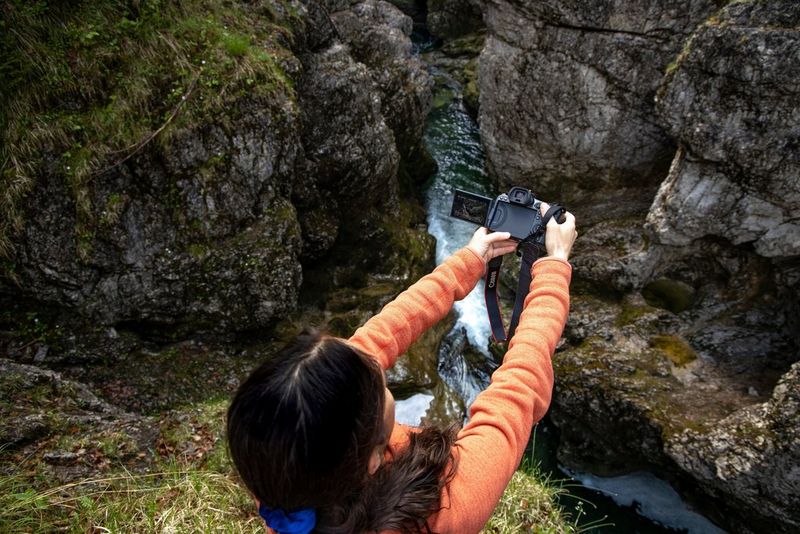 Fotograaf Ulla Lohmann houdt een EOS R5 op armslengte boven een afgrond en kadreert haar foto op het variangle scherm.
